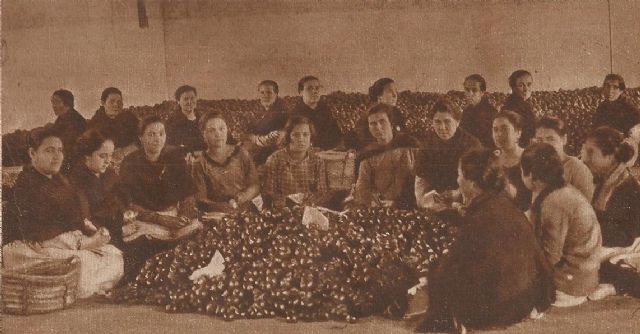 En esta imagen publicada por la revista Estampa el 17 de enero de 1931 se aprecia a un grupo de mujeres en plena faena de preparación de la naranja en uno de los almacenes de la localidad. Esta fruta, envuelta en papel de seda, se ofrecía como preciado regalo. La mujer totanera, implicada en la actividad naranjera, asumió la necesidad de reivindicar sus derechos laborales y planteó varias huelgas en defensa de los mismos.